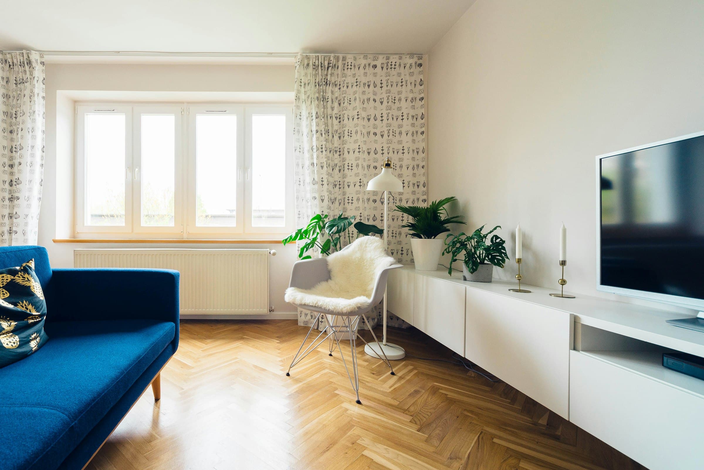 Salón real de uno de los pisos en alquiler, con suelo de espiga y sofá azul